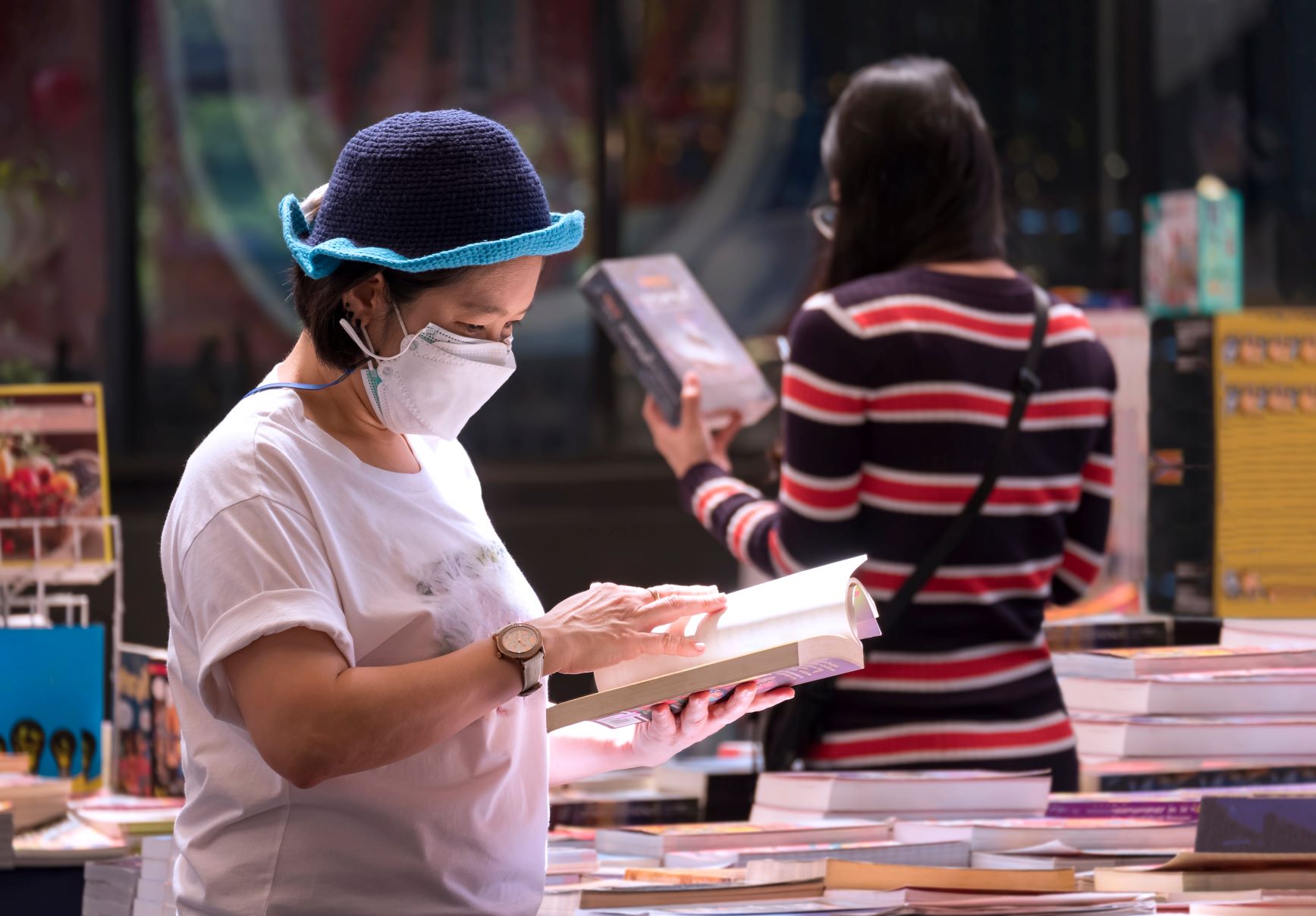 casual woman wears protective mask is choosing book